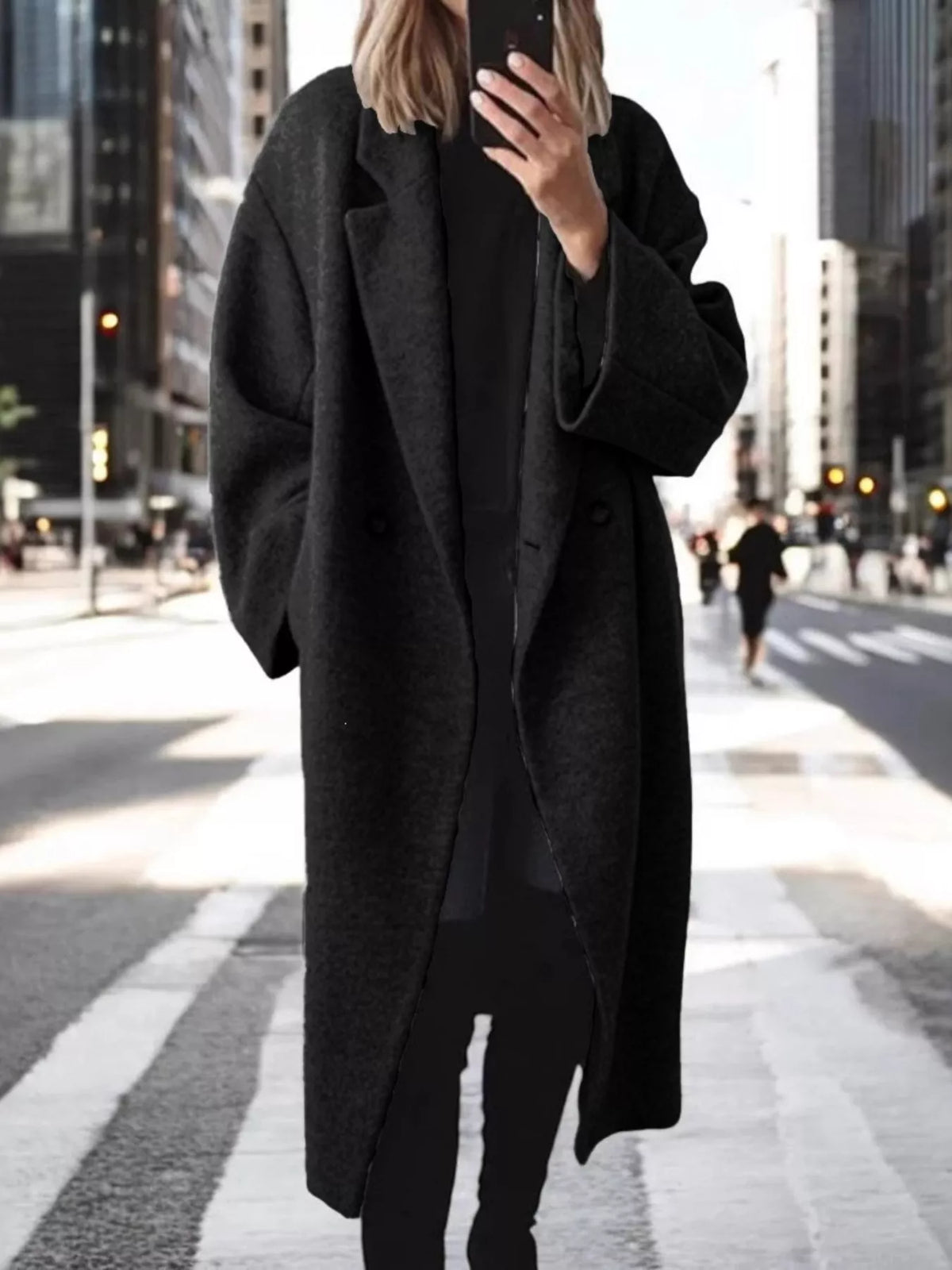 Front view of black longline coat with lapel collar and structured silhouette