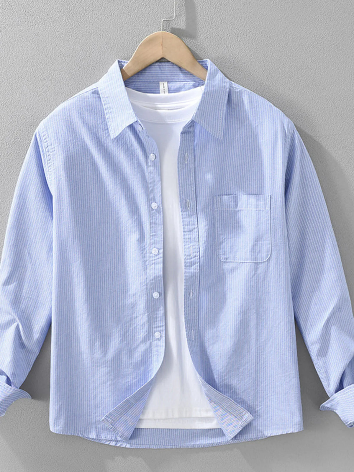 Model wearing the Season Prestige tailored striped long-sleeve button-up shirt in light gray layered over a white tee